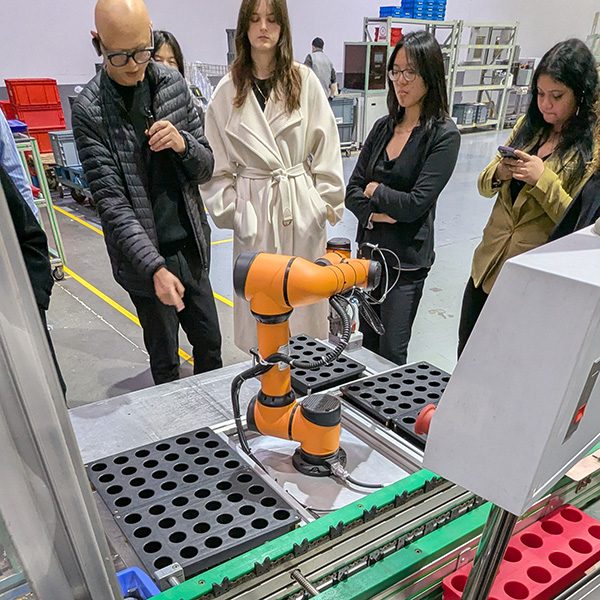 Un employé d'une entreprise chinoise de technologie de nettoyage explique l'utilisation des bras robotiques en automatisation à un groupe d'étudiants de Questrom.